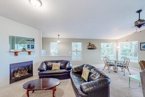 A living room with a fireplace, leather sofas, a coffee table, and a dining area with chairs and a table.