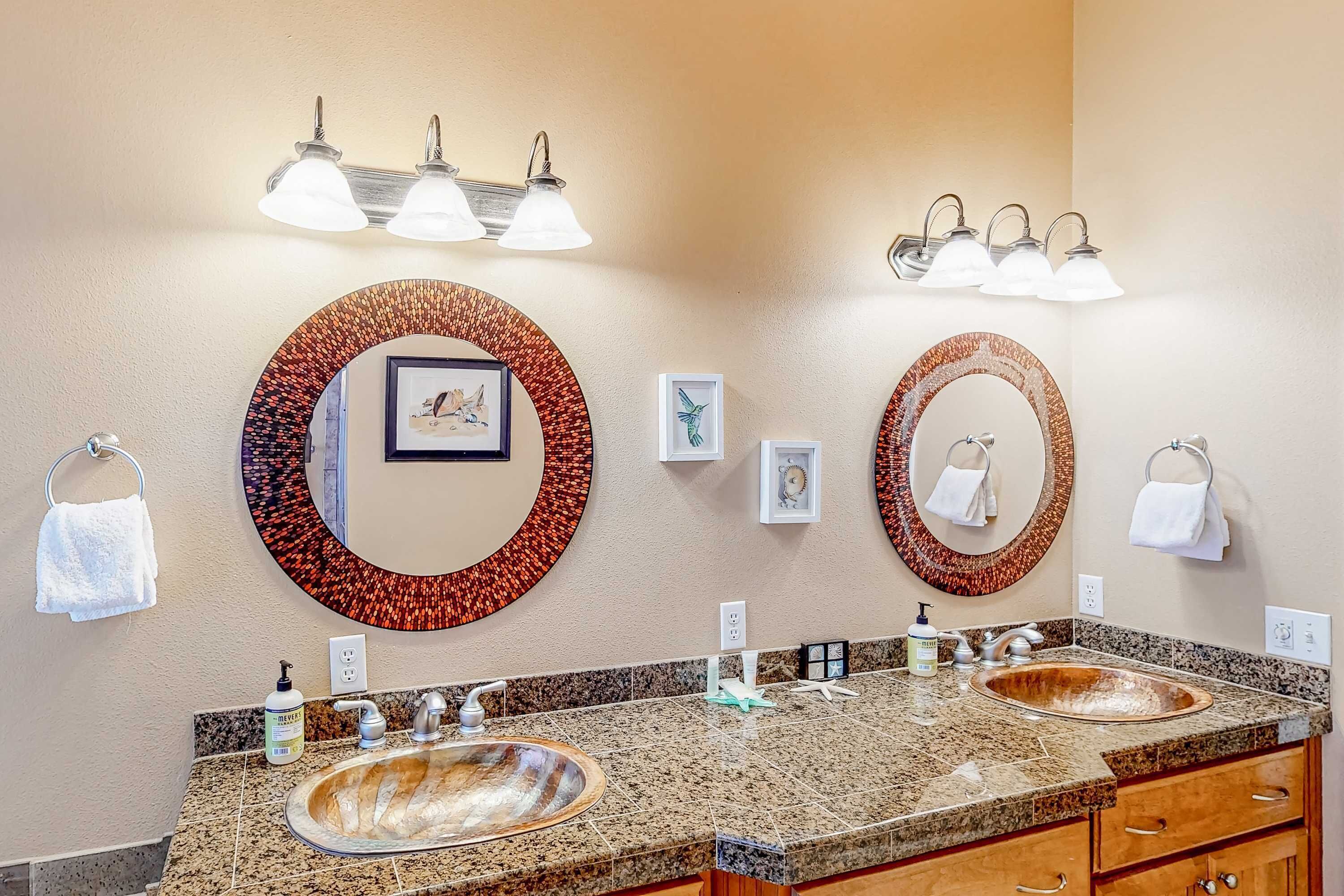 A bathroom with two sinks, granite countertops, and wall-mounted mirrors with decorative frames.
