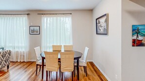 A dining area with a round table and chairs, a sofa, and artwork on the walls.