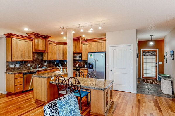 A kitchen with wooden cabinets, granite countertops, a built-in island with seating, and a refrigerator.
