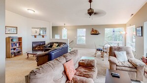 A spacious living room with a fireplace, a sofa, a recliner, and a bookshelf.