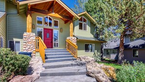 A house with a red door, stone pillars, and a wooden staircase leading to a porch. - Exquisite home with hot tub, golf on-site, pool, tennis, & washer&dryer (Eagle Crest)
