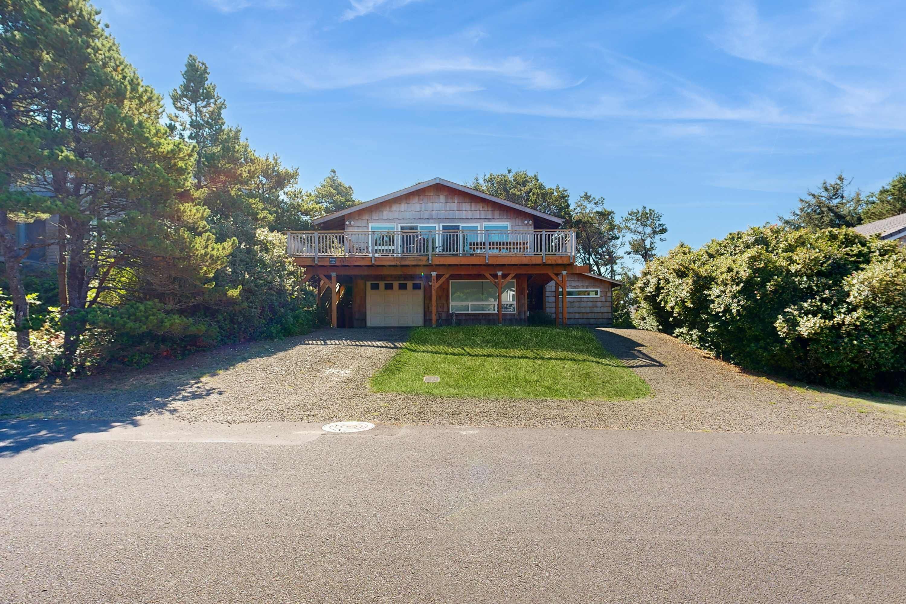 Une maison à deux étages avec un porche à l’avant, un garage et un balcon couvert.