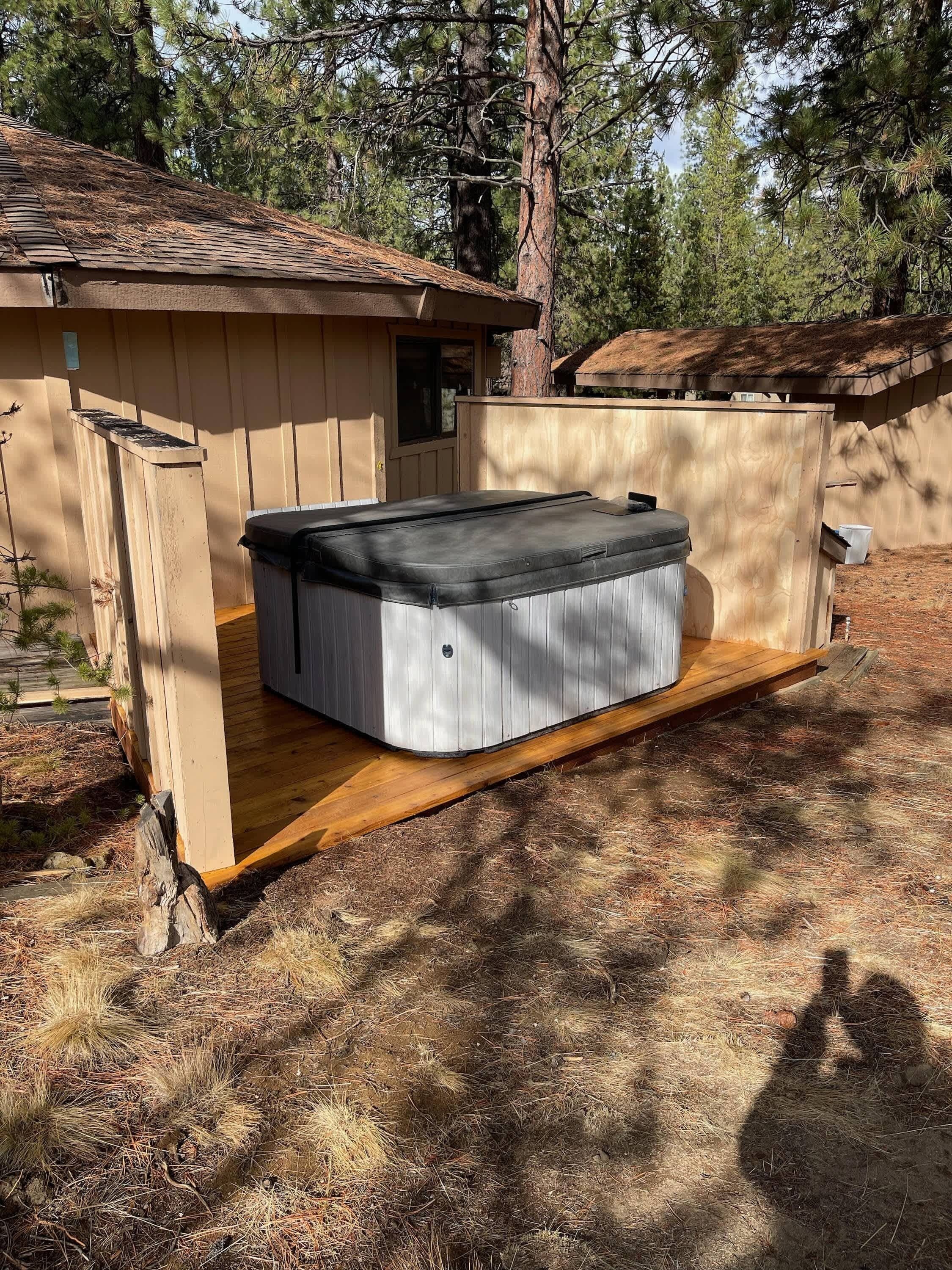 A hot tub in a wooden outdoor enclosure with a wooden deck and a door.