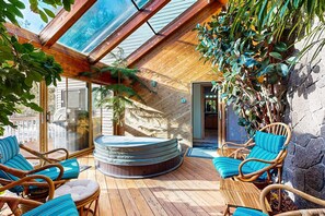 A sunlit outdoor deck with wicker furniture, a hot tub, and potted plants. - Stunning home with indoor hot tub, Ping-Pong table (Sunriver)