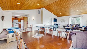 Un'ampia zona giorno con soffitto in legno, un tavolo da pranzo e un divano.