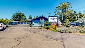 A motel with a sign reading 'LAMPLIGHTER INN ENTRANCE,' a parking lot, and a building with a blue exterior. - Retro beach experience with fast WiFI - walk to downtown shops & eateries (Bandon)