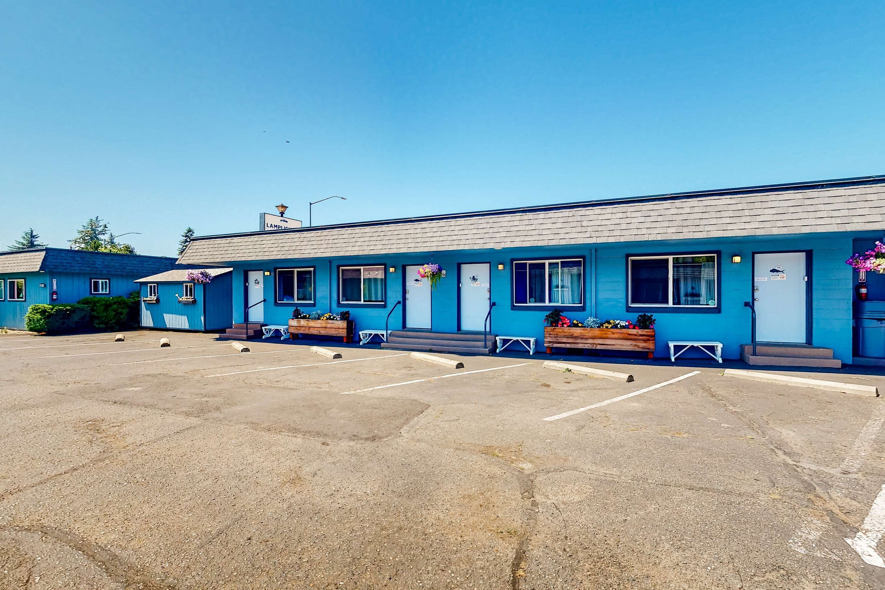 A blue building with a parking lot in front.