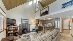 Ein Wohnzimmer mit Kamin, Fernseher und Küchenzeile mit Holzausstattung.