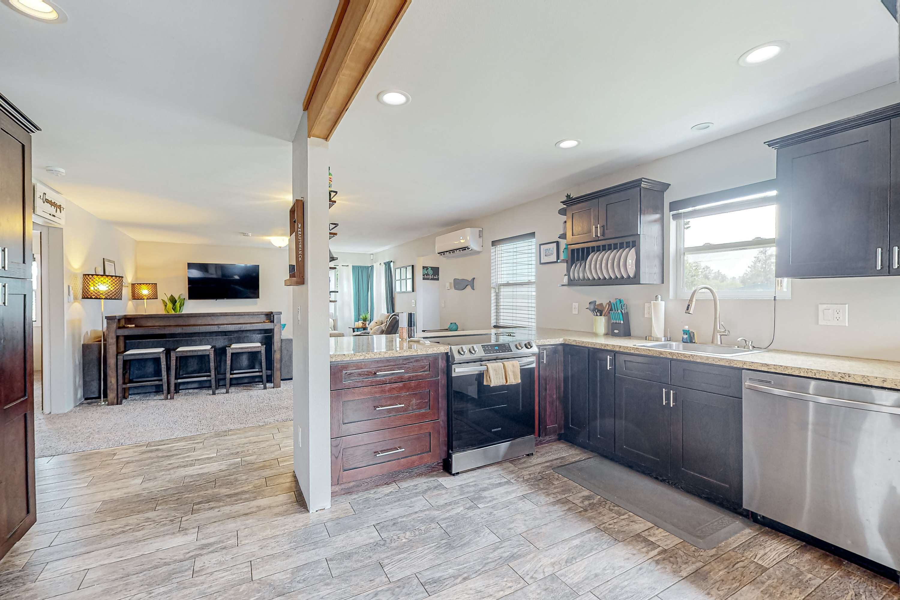 A modern kitchen with dark cabinets, stainless steel appliances, and a central island with seating.