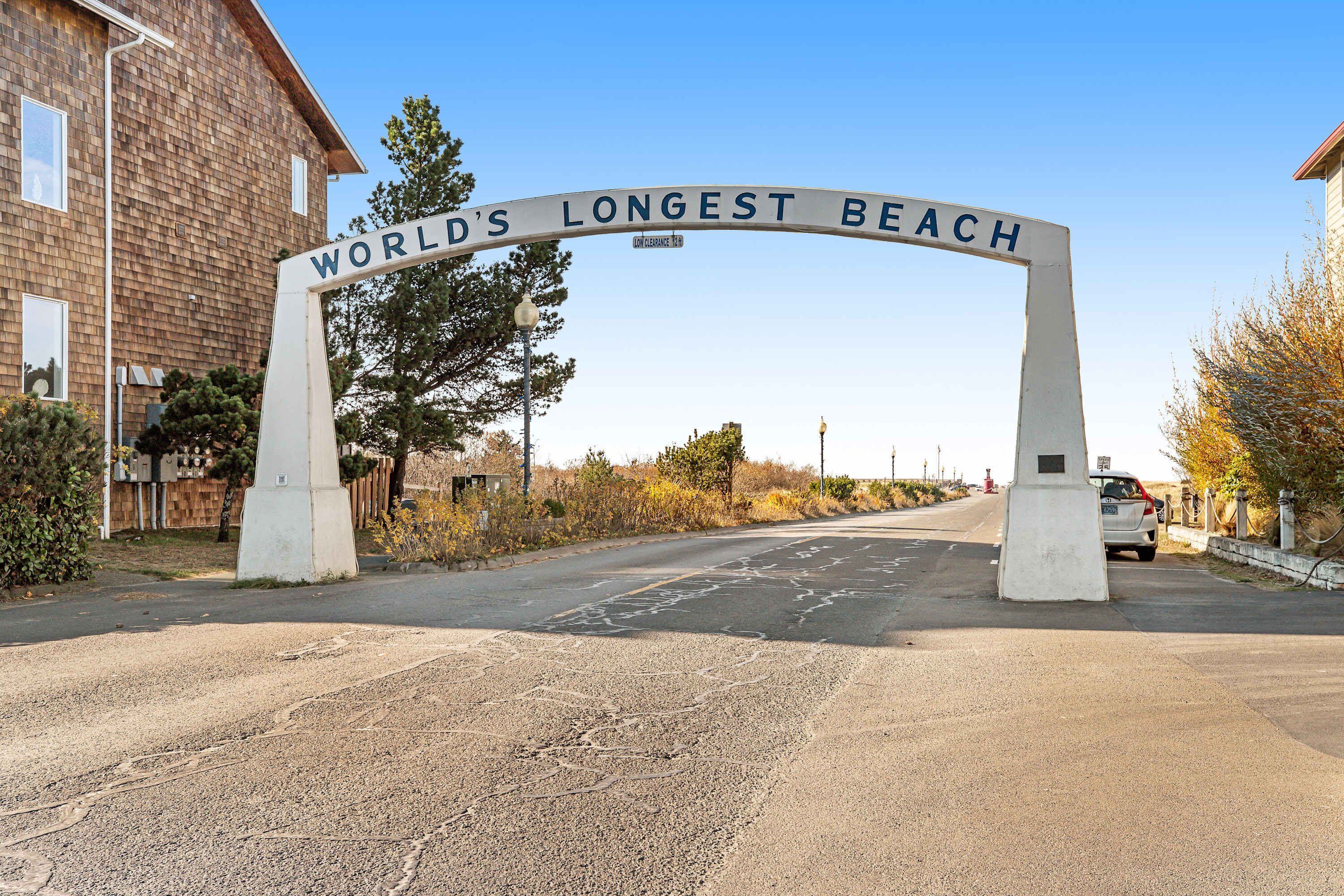 Een bord met de tekst 'WORLD'S LONGEST BEACH', een heldere lucht en een gebouw aan de linkerkant.
