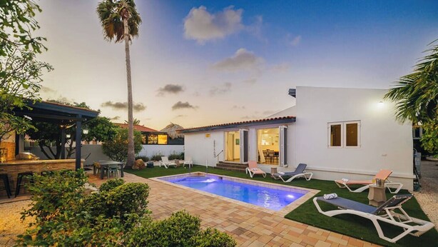 A backyard with a swimming pool, lounge chairs, a barbecue area, and a covered patio. - Modern villa in Safir (Noord) with private pool and outdoor kitchen. Minutes from Eagle & Palm Beach. Perfect for relaxing, dining outside, and enjoying Aruba’s best beaches in comfort and style. (Noord)