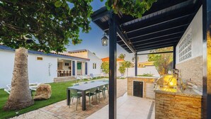 A covered outdoor patio with a dining table and chairs, a barbecue grill, and a pool area. - Modern villa in Safir (Noord) with private pool and outdoor kitchen. Minutes from Eagle & Palm Beach. Perfect for relaxing, dining outside, and enjoying Aruba’s best beaches in comfort and style. (Noord)