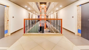 Un moderno vestíbulo de hotel con una escalera central, varias puertas y un suelo de baldosas.