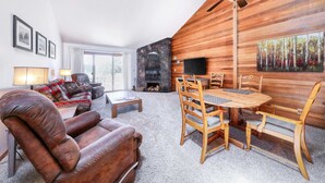 Una sala de estar con chimenea, una mesa de comedor con sillas, un sofá y un televisor.