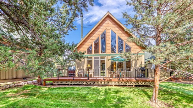 Une maison en bois avec de grandes fenêtres, une terrasse et une pelouse.
