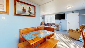 En matplats med ett träbord och bänkar, en tv som är monterad på väggen och en dörr med en klocka.