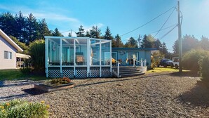 Ett modernt hus med en inglasad veranda, en grusuppfart och ett fordon parkerat i närheten.