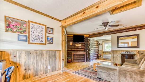 A log cabin interior with wooden floors, a fireplace, a television, and a sofa. - Mountain & valley-view dog-friendly cabin with courtyard, partial AC, and WiFi (White Salmon)