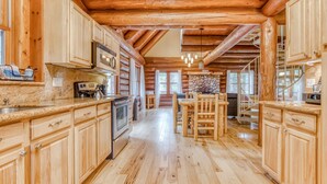 Een houten blokhut interieur met houten vloeren, een keuken met granieten aanrecht en een eethoek met houten meubels.
