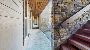 A covered outdoor corridor with a stone wall and wooden steps. - Dog-friendly ground-floor condo with pools, hot tubs, sauna, & fitness room (Bend)