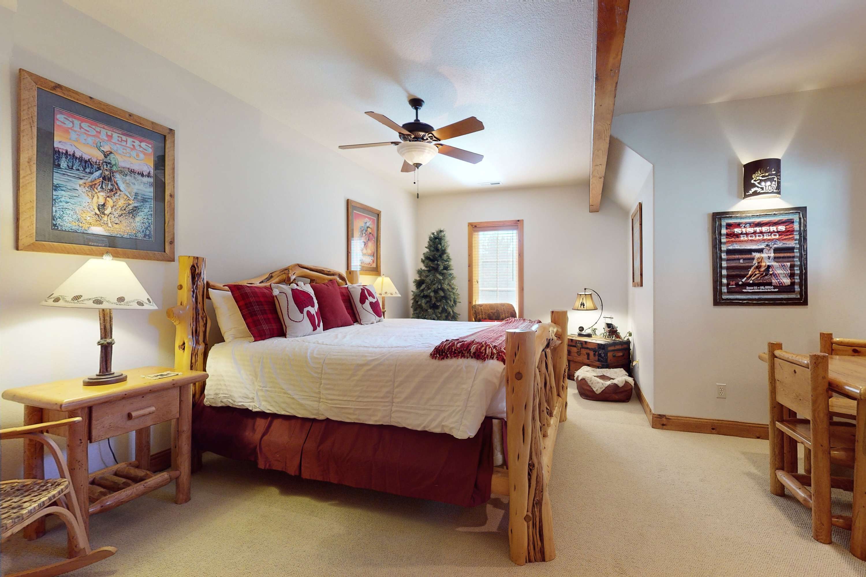 A bedroom with a bed, wooden furniture, a ceiling fan, and wall decorations.