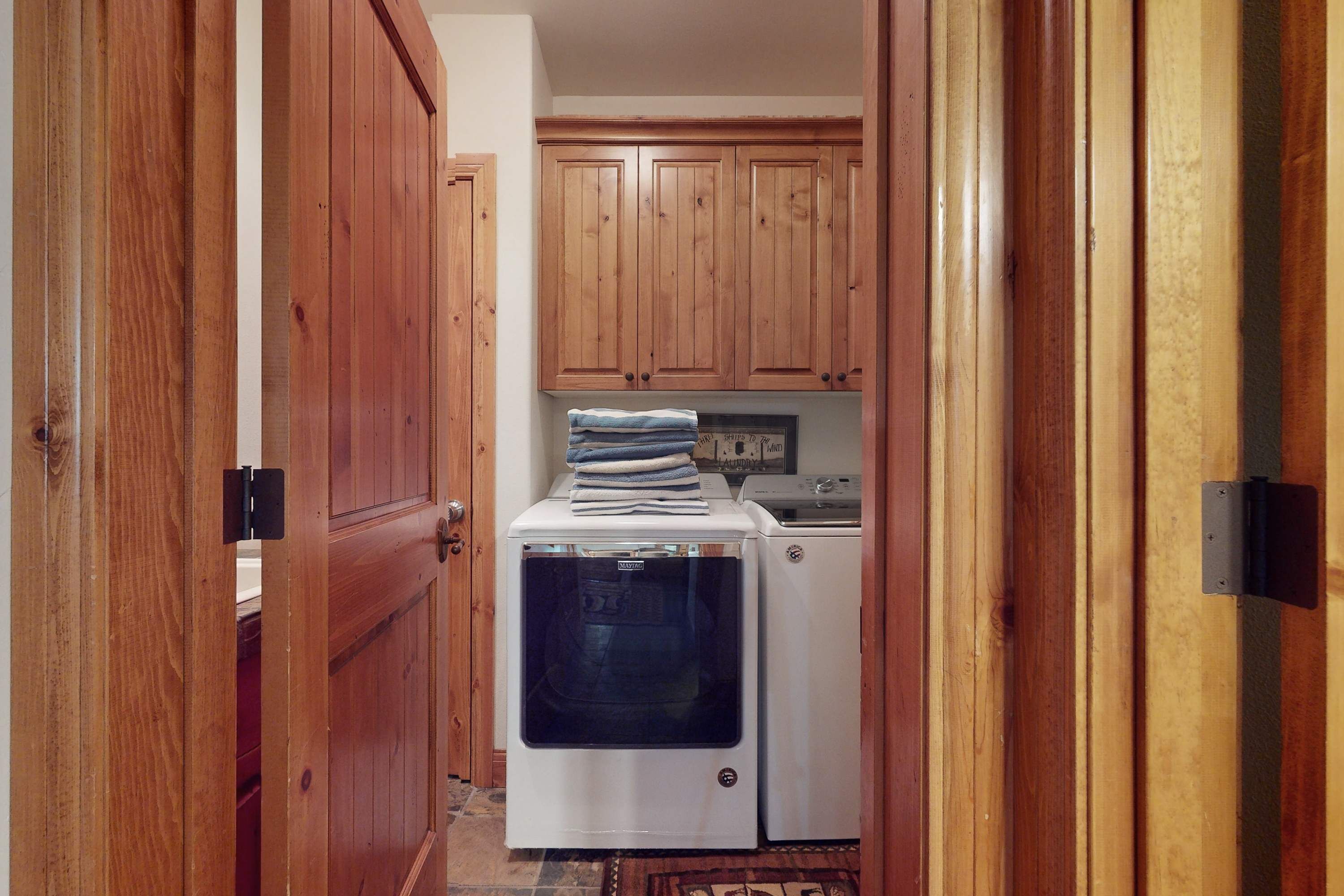 A narrow hallway with wooden cabinets, a white washing machine, and a dryer.