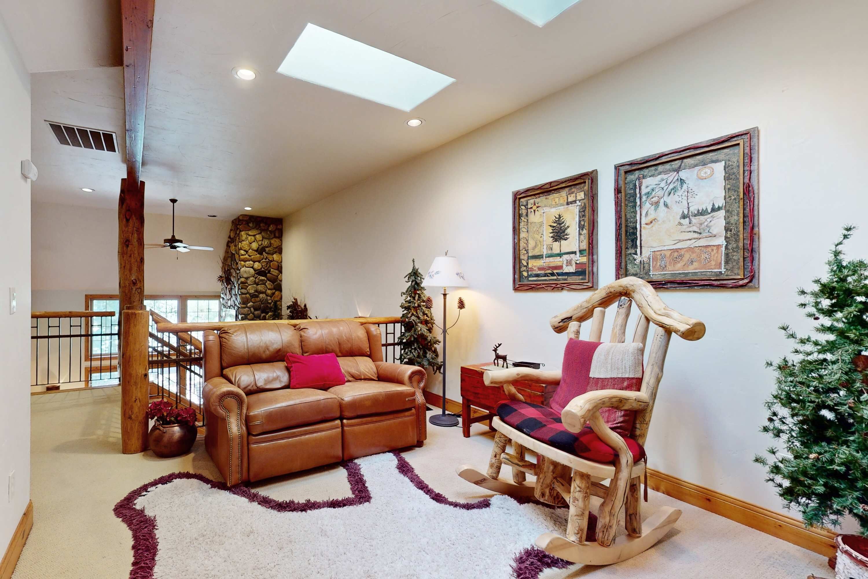 A spacious living room with a leather sofa, a rocking chair, and a Christmas tree.