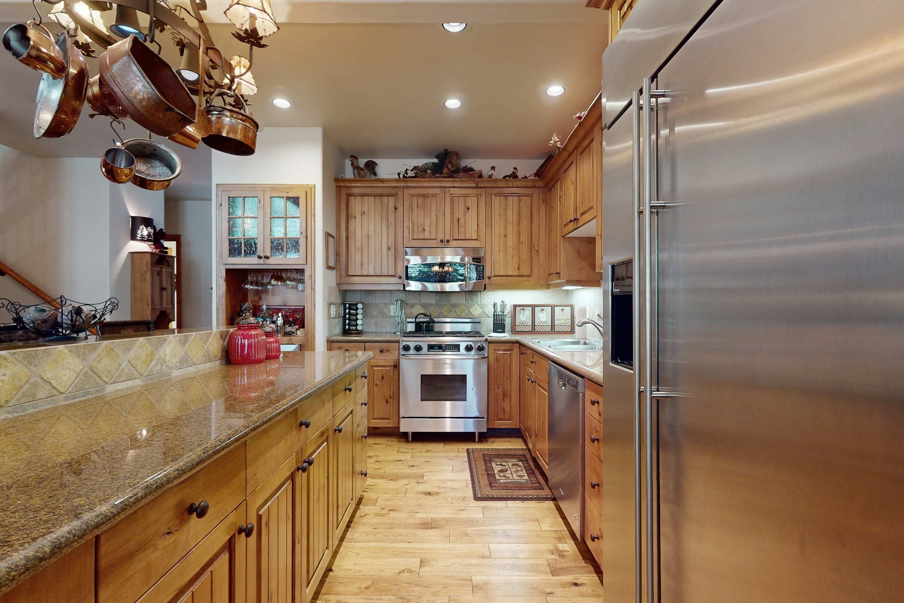 A kitchen with wooden cabinets, stainless steel appliances, and a granite countertop.
