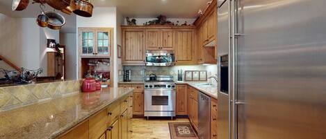 A kitchen with wooden cabinets, stainless steel appliances, and a granite countertop.