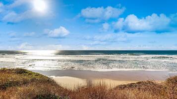 A beach with waves, a clear sky, and a sun.