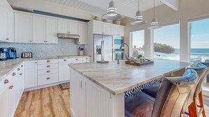 Een moderne keuken met witte kasten, een groot eiland en hanglampen.