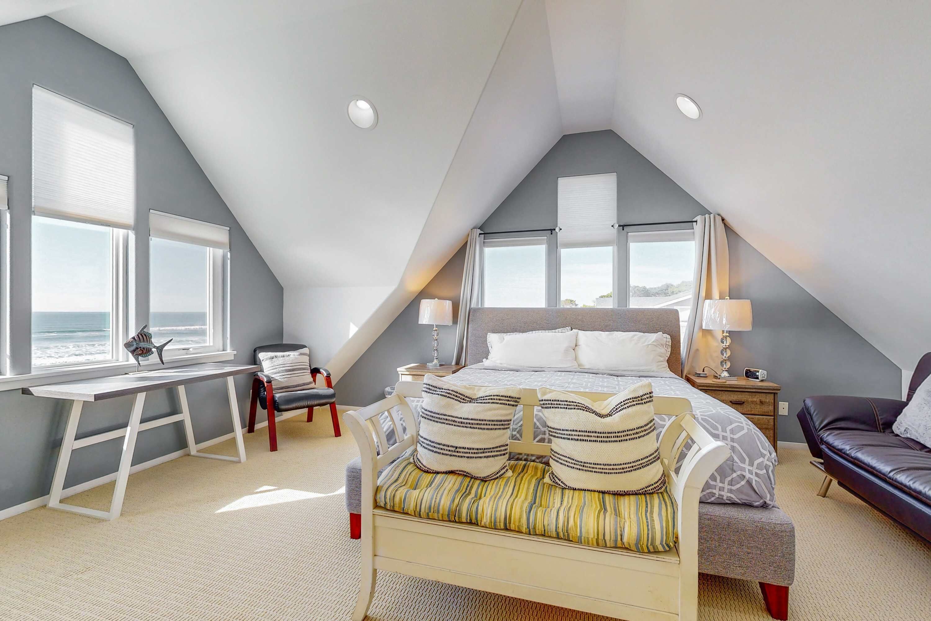 Ein Schlafzimmer mit Bett, Schreibtisch, Stuhl und Meerblick.
