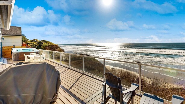Een terras met een jacuzzi, stoelen en uitzicht op de oceaan.