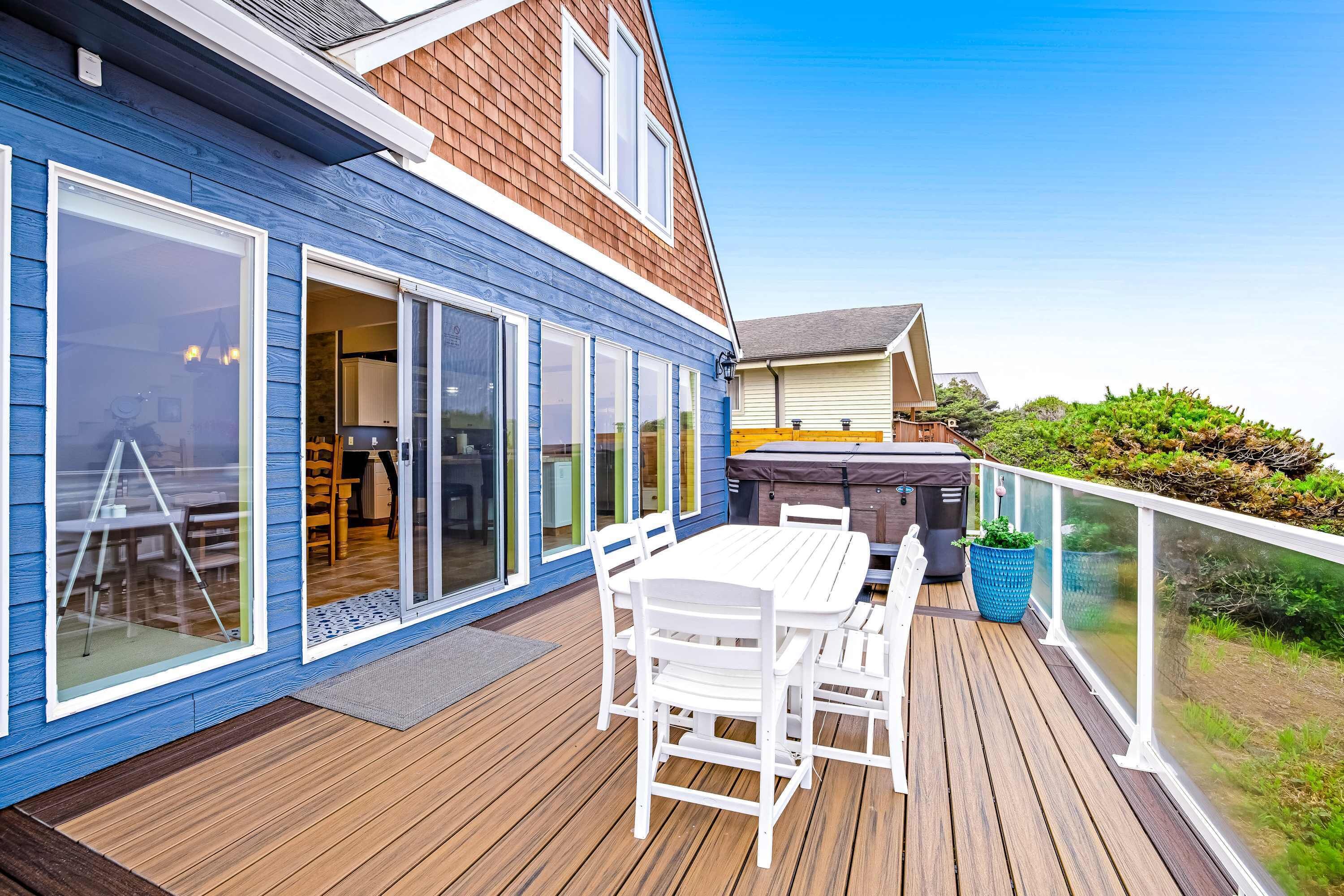 A deck with a table and chairs, a grill, and a large window.