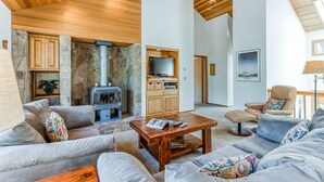 A spacious living room with a stone fireplace, a television, and a comfortable seating area. - Comfortable Sunriver Home with Private Hot Tub and WiFi - Free SHARC Access (Sunriver)