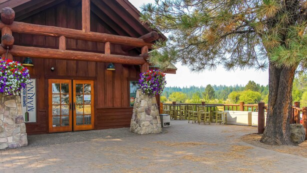 A log cabin-style building with stone pillars, wooden doors, and hanging flower baskets. - Comfortable Sunriver Home with Private Hot Tub and WiFi - Free SHARC Access (Sunriver)