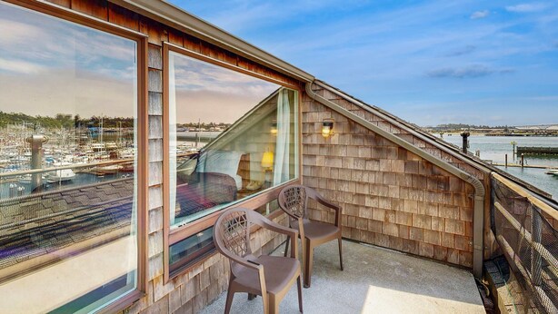 Ein Balkon mit Blick auf einen Yachthafen, Holzwände und zwei Stühle.