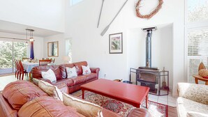 A living room with a sofa, coffee table, fireplace, and a dining area with chairs and a table. - Charming cabin with patio, firepit, fast WiFi, full kitchen, & W&D (Manzanita)