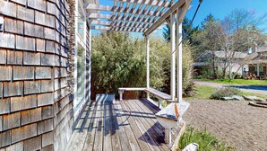 A wooden deck with a pergola, a bench, and a small birdhouse. - Charming cabin with patio, firepit, fast WiFi, full kitchen, & W&D (Manzanita)