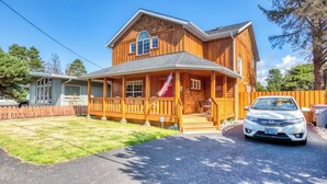 A two-story wooden house with a porch, a car parked in front, and a clear blue sky. - Updated home with fireplace & media room - 2 blocks to the beach & promenade (Seaside)