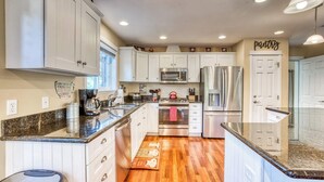 A modern kitchen with white cabinets, stainless steel appliances, and a wooden floor. - Updated home with fireplace & media room - 2 blocks to the beach & promenade (Seaside)