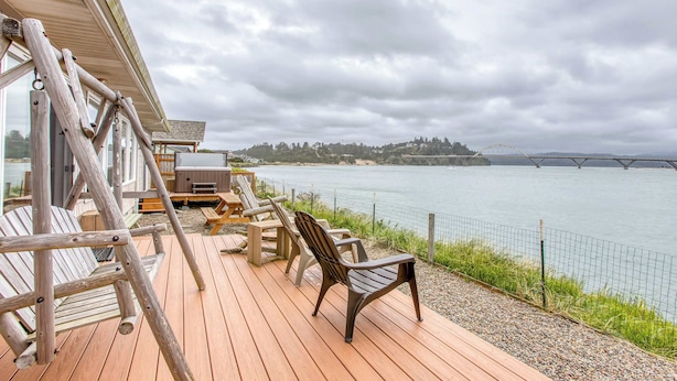 Un pontile in legno con posti a sedere all'aperto, con vista su un corpo d'acqua e un ponte.