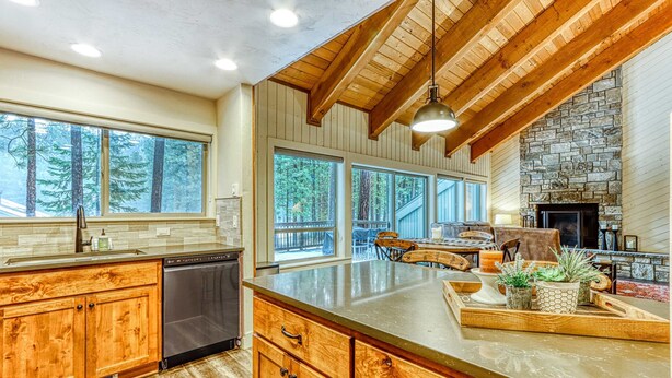 A kitchen with wooden cabinets, a dishwasher, and a stone fireplace. - Dog-friendly home next to South Meadow pool with fireplace & washer&dryer (Black Butte Ranch)