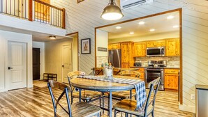 A dining area with a round table, chairs, and a hanging light fixture. - Dog-friendly home next to South Meadow pool with fireplace & washer&dryer (Black Butte Ranch)