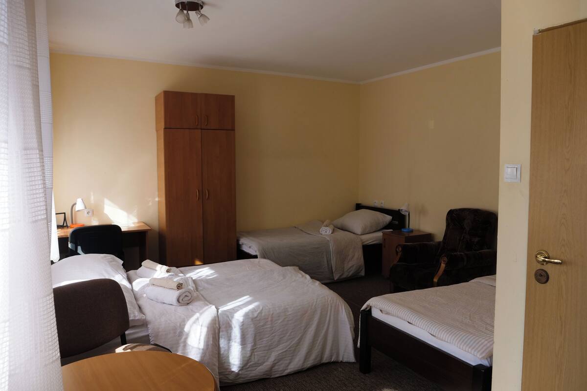 Une chambre d’hôtel avec deux lits, une armoire en bois, un bureau avec une lampe et une chaise.