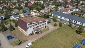 A multi-story building with a flat roof, surrounded by a residential area with houses and trees. - Hotel Sowa (Częstochowa)