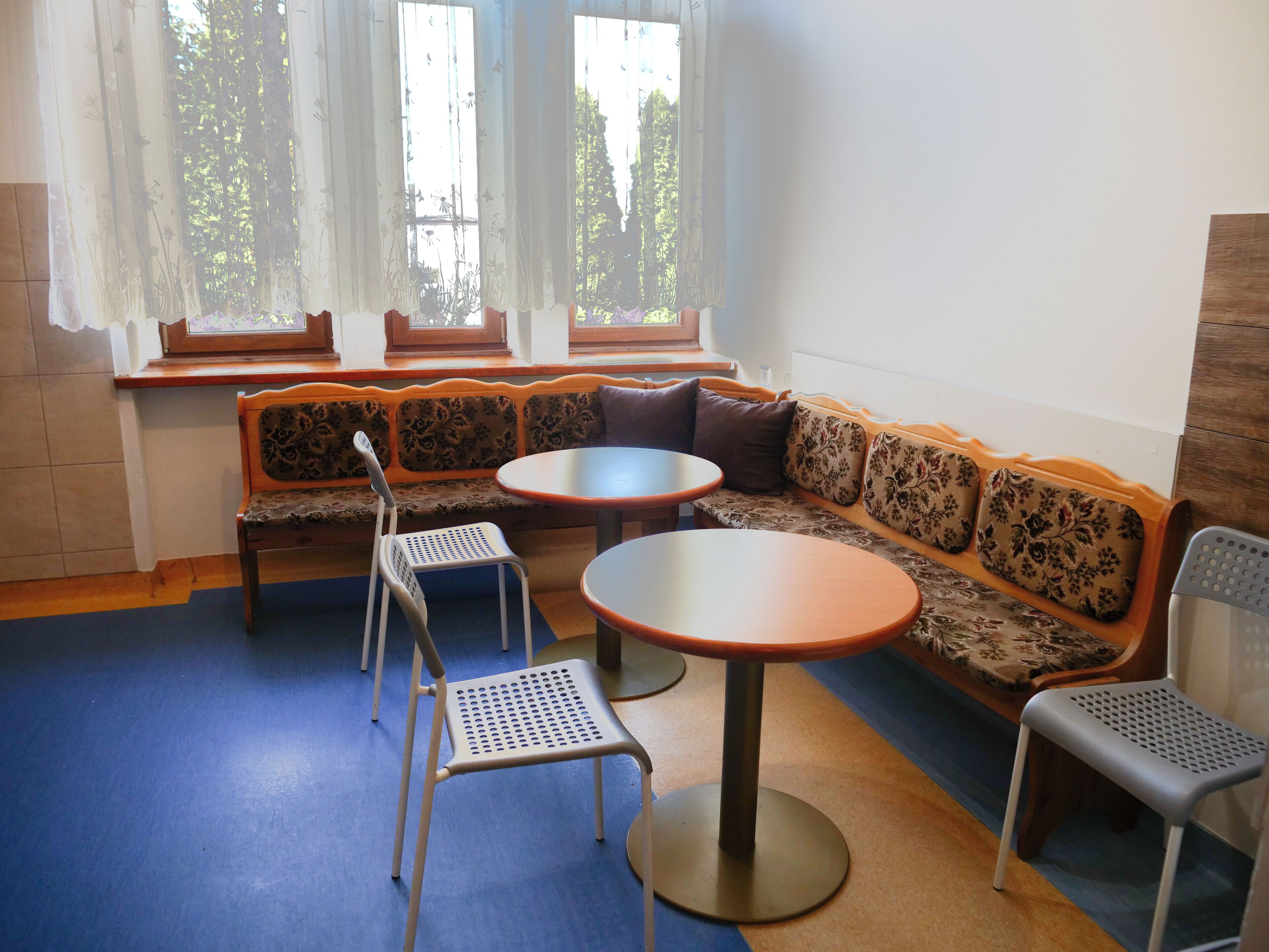 A seating area with a sofa, two round tables, and two chairs.