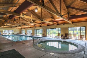 Une piscine intérieure avec un plafond en bois, de grandes fenêtres et des chaises longues.