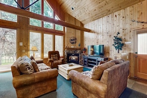 Un intérieur en bois avec une cheminée, des canapés, un téléviseur et un manteau de cheminée en pierre.